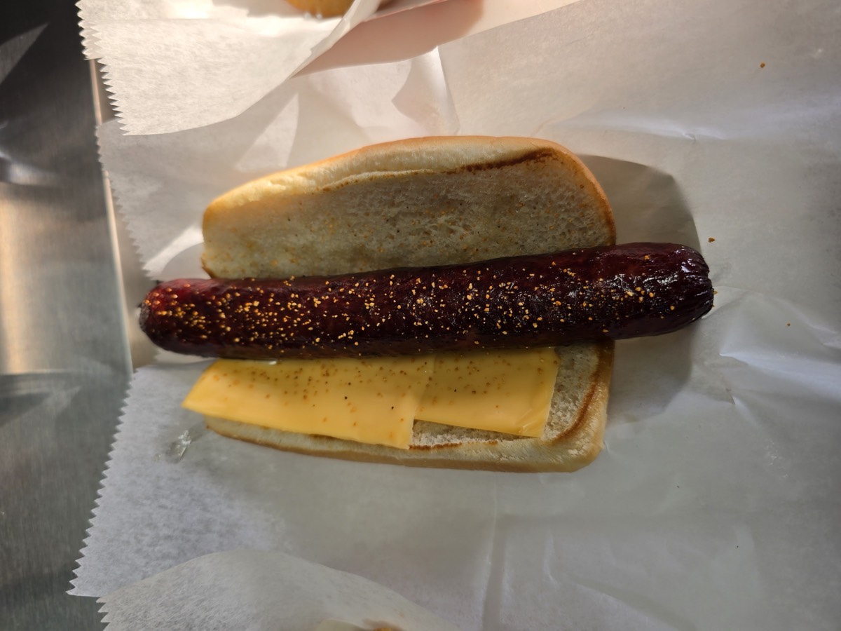 Deep fried jumbo quarter-pound hot dog nestled in a bun with cheese