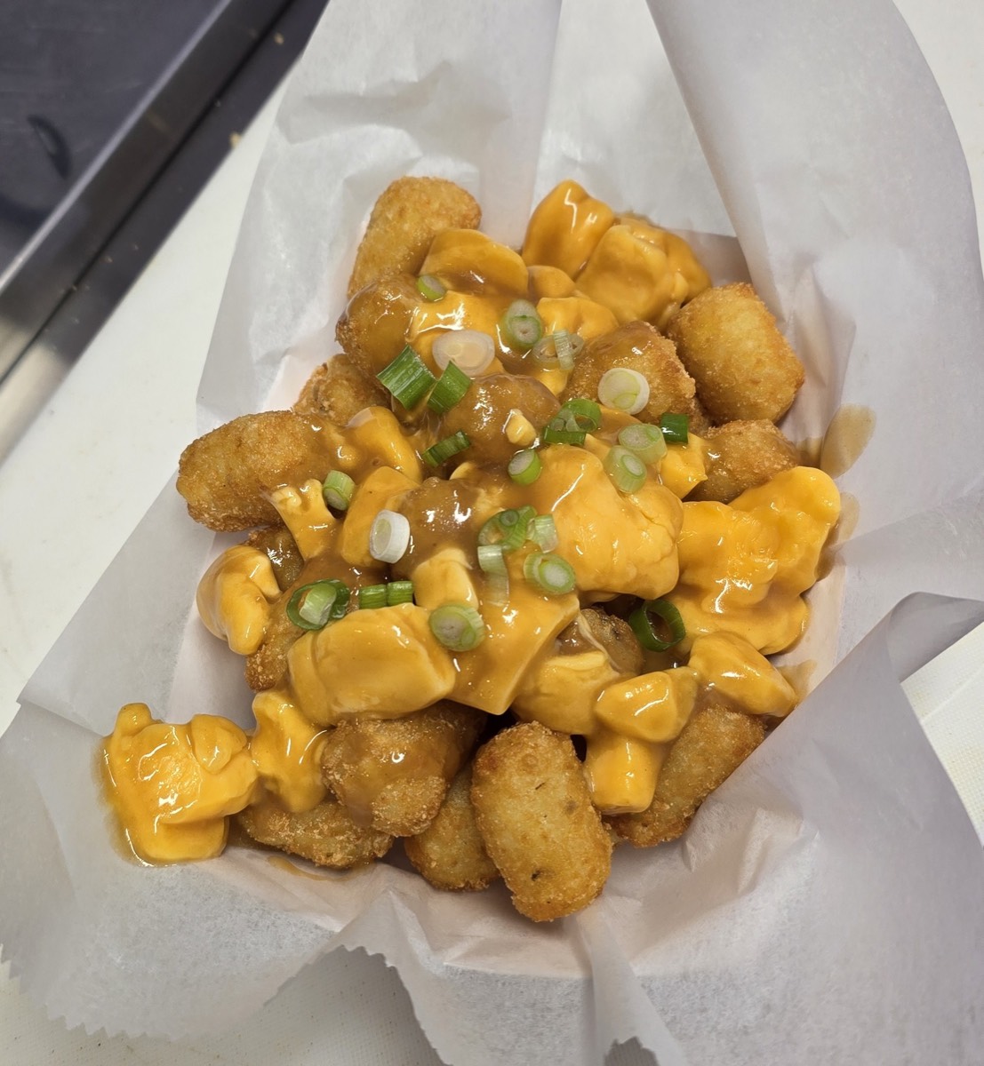 Crispy tots topped with cheese curds, brown gravy and sliced green onions