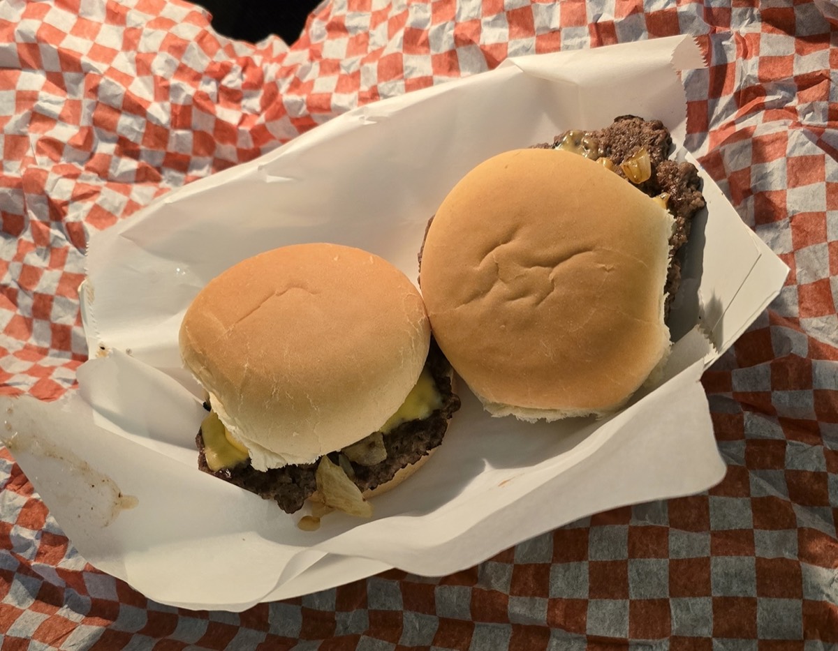 Two smashburger sliders with melted cheese in a paper-lined basket